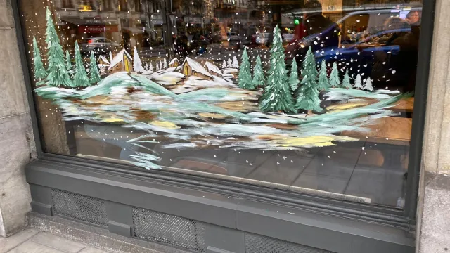 Paysage d’hiver avec sapins peint sur une vitrine
